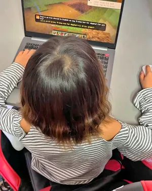 A child playing Minecraft on a laptop, seen from above